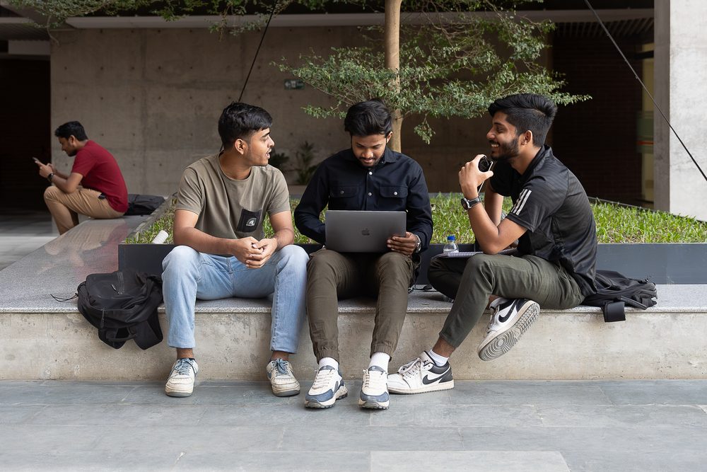 Three UIU students working on a laptop in the campus courtyard